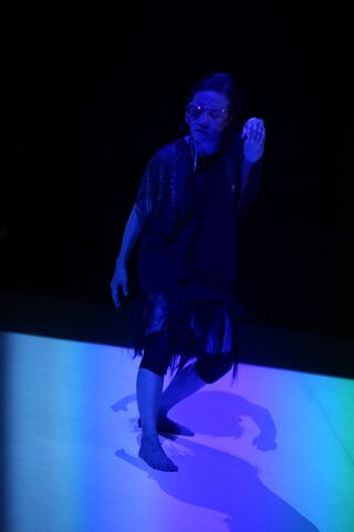 Koosil-ja in a black ensemble dancing in dim lighting giving off a sinister tone
